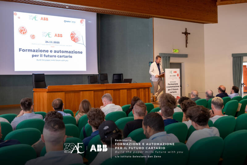 Intervento del responsabile didattico durante il seminario “Formazione e automazione per il futuro cartario” all’Auditorium dell’Istituto Salesiano San Zeno (24 giugno 2025), con platea in ascolto e slide proiettata.